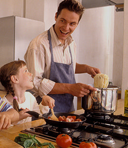 Father and daughter sharing joyful moments in the kitchen, laughing together while cooking on a gas cooktop