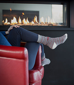 Cozy evening by the fireplace: A person sits in a red chair next to a gas-powered see-thru fireplace, enjoying warmth and relaxation
