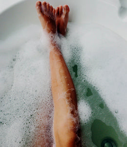 Relaxed legs peeking out from a steaming bubble bath, bringing comfort and tranquility to the moment