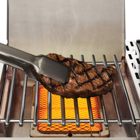 Juicy steak sizzling on BroilKing Baron S 590 IR grill's infrared side burner, emitting mouthwatering aromas and perfect sear marks