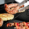 Close-up of grill tongs flipping grilled sausage and pineapple on BroilKing Crown 420, sizzling with deliciousness
